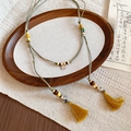 Detailed close-up of handmade ethnic waist chain necklace with beads and yellow tassels - Green and Yellow Braided Style