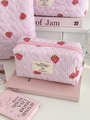 Roze gestreepte gewatteerde make-uptas met aardbeienprint en ritssluiting op een tafel - Achthoekig Tasje