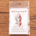 Pocket Hug Heart wing pendant with red enamel and message card on wood background - Angel & Devil Wings Heart