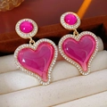 Vue macro de boucles d'oreilles cœur rose avec base dorée et détails de cristaux blancs - Rose Magenta (Tige en argent S925)