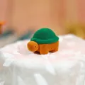 Dettaglio macro di un portanelli a forma di tartaruga in velluto su pizzo bianco - Verde