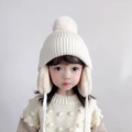 Kinder Strickmütze in Elfenbein mit Bommel und Ohrenklappen für den Winter warm - Einheitsgröße(Elastisch) / Creme