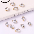 Detailed view of gold bow pendants with sparkling zircons scattered on a white book - Simple Zircon Inlaid Large 8mm