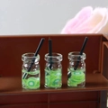 Detailed close-up of miniature kiwi juice bottles with realistic fruit slices and black straws - Fruit Cup 8