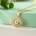 Boho Goldhalskette mit Evil-Eye-Anhänger und Zirkonia auf grünem Podest präsentiert - Blau-Weißer Böser Blick