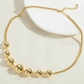 Detail einer 14K vergoldeten Perlenkette mit verstellbarem Karabinerverschluss auf Weiß - Halskette / Gold