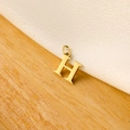 Macro shot of polished gold H letter pendant with ring clasp on a textured background - 14k Letter - H (letter Height 1cm)