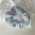 Detailaufnahme eines hellblauen Haargummis mit Blasenstruktur auf weißem Papier - Blau