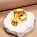 Artistic golden face brooch with blue eye detail and silver nose ring accent - Gold
