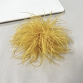 Detailed view of a bright yellow ostrich feather brooch on a grey textured background - Gold