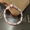 Detailed close-up of a pink quartz crystal bead bracelet with silver spacers on a raw stone - Rose Quartz