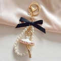 Detailed macro view of ballet girl charm with rhinestones, pearls and a black silk bow - White + Bowknot Pearl String