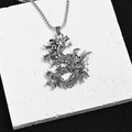 Vue détaillée du pendentif dragon en argent vintage sur une pierre blanche plate - Dragon en Relief 3D