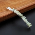 Close-up of silver hair clip with pale green natural crystal stones on wood surface - Prehnite with Silver Clip