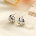 Detailed macro shot of silver geometric C-shaped earrings on stone with flower petals - Silver Style (ZYN-DME514P) / Silver
