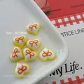 Detailed view of 8mm and 10mm resin heart charms with orange bows for nail art - White Yellow