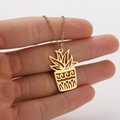 Detailed close-up of a gold plant pot pendant necklace with intricate cutout leaf designs - No.904 Plant / Gold