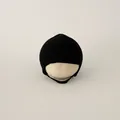 Detail of black knitted baby hat with earflaps and chin straps on wooden display - 4-16 Months (38-46cm) / Black