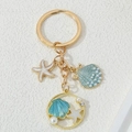 Ocean theme keychain with gold shell and starfish charms on a white textured background - Blue White Pearl Ocean Mix