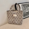 Dettaglio della borsa tote in tela con pois rossi e fiocchi su un tappeto crema - Grigio