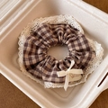 Detailed view of plaid scrunchie with lace trim, ribbon bow, and small fabric label - Coffee Plaid With Bow and Lace