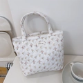 Detail der geblümten Stepp-Stofftasche mit aufgenähtem 'simple wish' Etikett auf Stoff - Gelbe und Rosa Blumen auf Weiß
