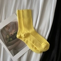 Vertical rib knit crew socks in vibrant yellow color placed on a fashion magazine - Short Lemon Yellow