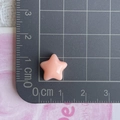 Close-up of a pink resin star charm on a cutting mat showing 1.5cm size detail - Orange
