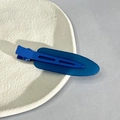 Detailed view of a blue matte duckbill hair clip on a textured white ceramic plate - Dark Blue
