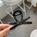 Detail of high-gloss black acrylic bow hair claw clip with strong metal spring - Glossy Black
