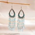 Détail de boucles d'oreilles bohèmes en goutte avec perles bleues sur fond de soie - Bleu clair