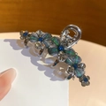 Vue détaillée de la pince à cheveux fleurie argentée avec paillettes et strass bleus - Fleur Dégradé Bleu-Vert (Base Noir Fusil)