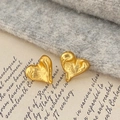Detailed macro view of golden heart earrings with unique lava texture on vintage paper - Lava Heart / Gold