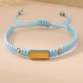 Detail of hand-woven light blue cord bracelet with a polished gold metal plate and beads - Light Blue (Gold Plate)