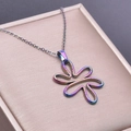 Macro shot of abstract floral pendant with rainbow metal plating on pink jewelry box - Pendant Necklace / Rainbow