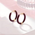 Elegant gold earrings with burgundy red enamel finish shown on a white geometric stand - Wine Red