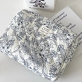Neceser de algodón acolchado con motivos florales azules y etiqueta de tela sobre blanco - Clutch Bag