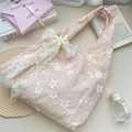 Détail de broderie florale et grand nœud en dentelle sur un sac cabas rose - Broderie de Fleurs Roses avec Grand Nœud