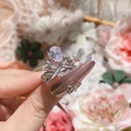 Detalle de anillo de corona plateado con circón de pera llevado en mano con flores - Abierto Ajustable / Plata Circonita Blanca