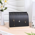 Detail of black leather necklace display stand with natural wood base in a modern setting - Black Leather