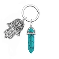 Macro shot of silver Hamsa hand charm and turquoise hexagonal crystal pendant on keychain - Turquoise