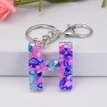 Close-up of letter H resin keychain with colorful stones and silver metal ring - Letter H