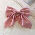Elegant pink satin bow hair clip in academy style placed on soft white fabric - Pink