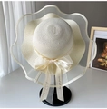 Detail of elegant cream straw hat featuring a wavy tulle brim and printed ribbon bow - Cream