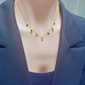 Gold butterfly necklace with green rectangular zircons and stars on a model's neck - Pentagram