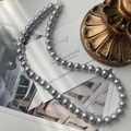 Detailweergave van de grijze parelketting met ronde kralen en zilveren sluiting op kaarten - 8mm Grijze Parel