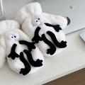 Detail showing plush white monster gloves with large eyes on a desk workspace - Quirky Monster Style (White)