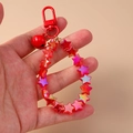 Cute red star beaded keychain with metal bell and lobster clasp shown on a plain background - Red