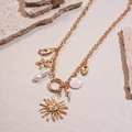 Detailed macro view of golden sun, seashell, and pearl pendants on layered chain - Golden Sun Face