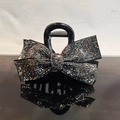 Detailed view of medium black hair claw clip with sparkling rhinestone bow on glossy surface - Mineral Grey Rhinestone